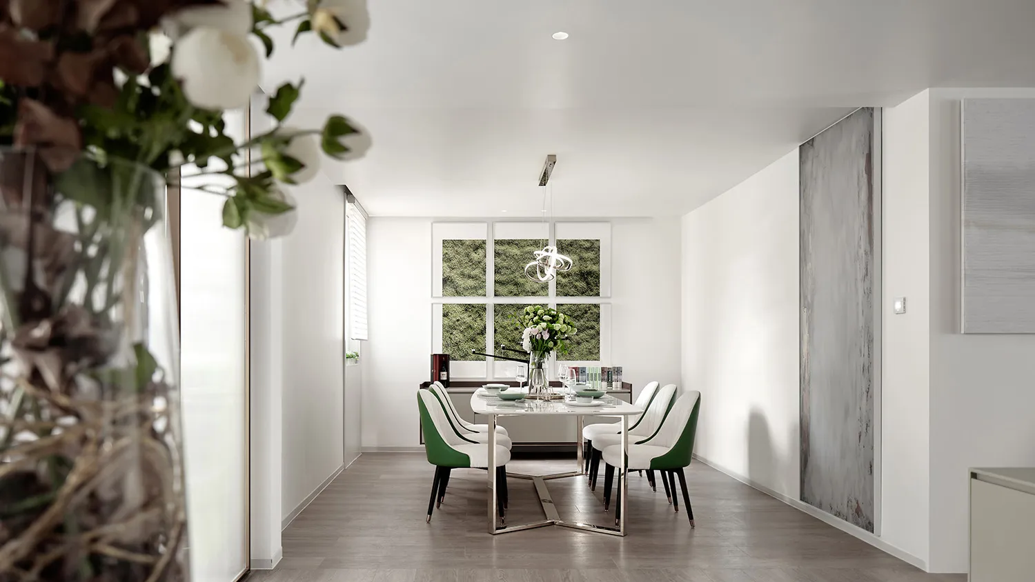 A modern minimalist dining space featuring a white marble table and white chairs with green accents.