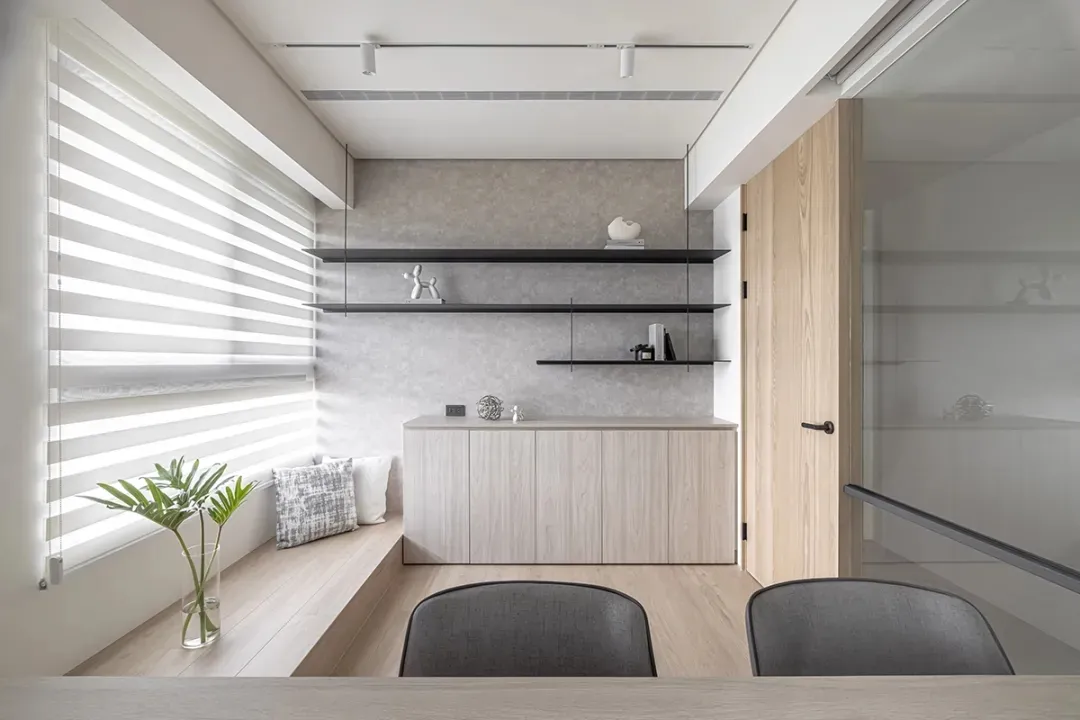 A minimalist office space with glass walls and wooden furniture, featuring a desk, chairs, and storage units.