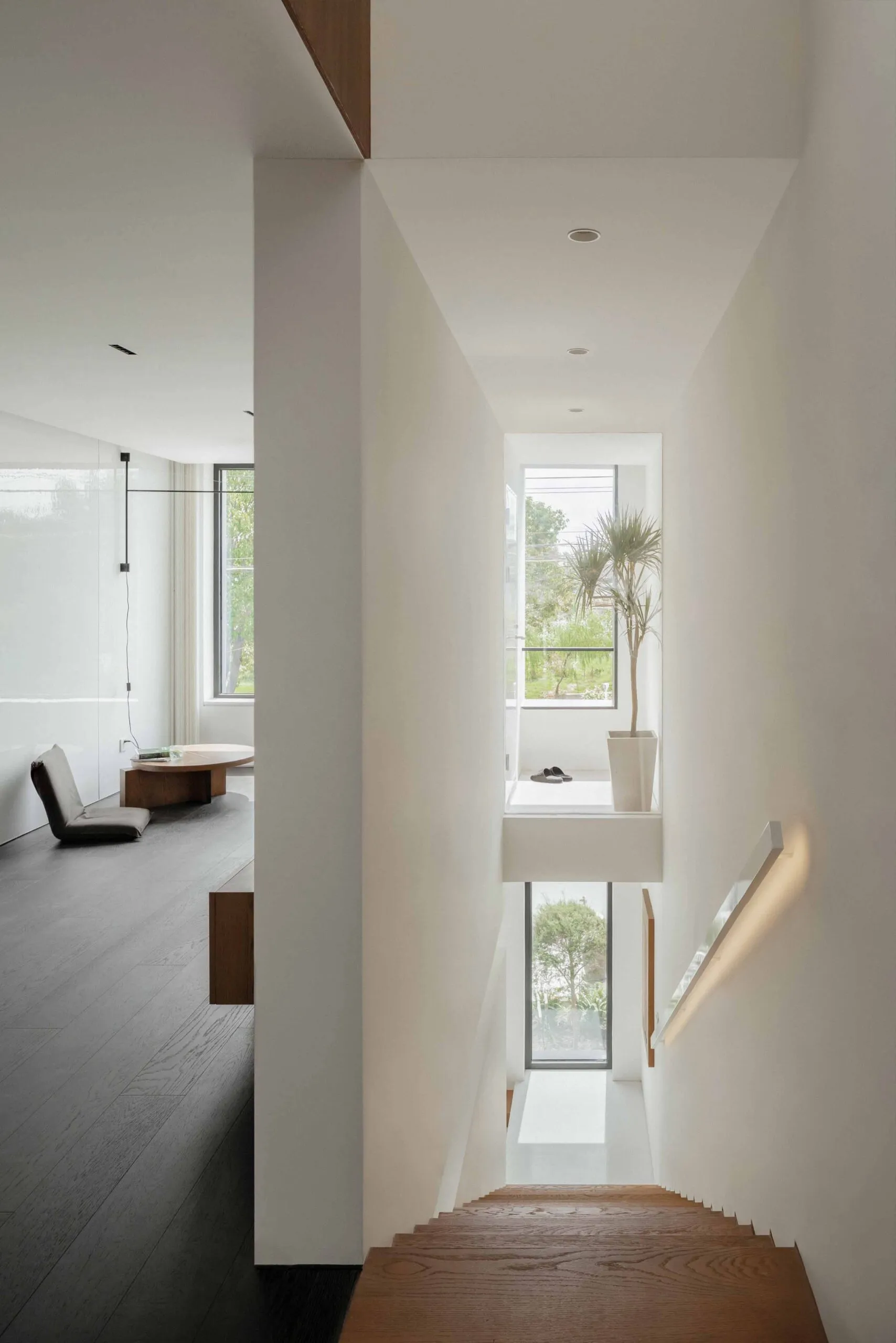 Modern white staircase with wood steps, white walls, and a light fixture.
