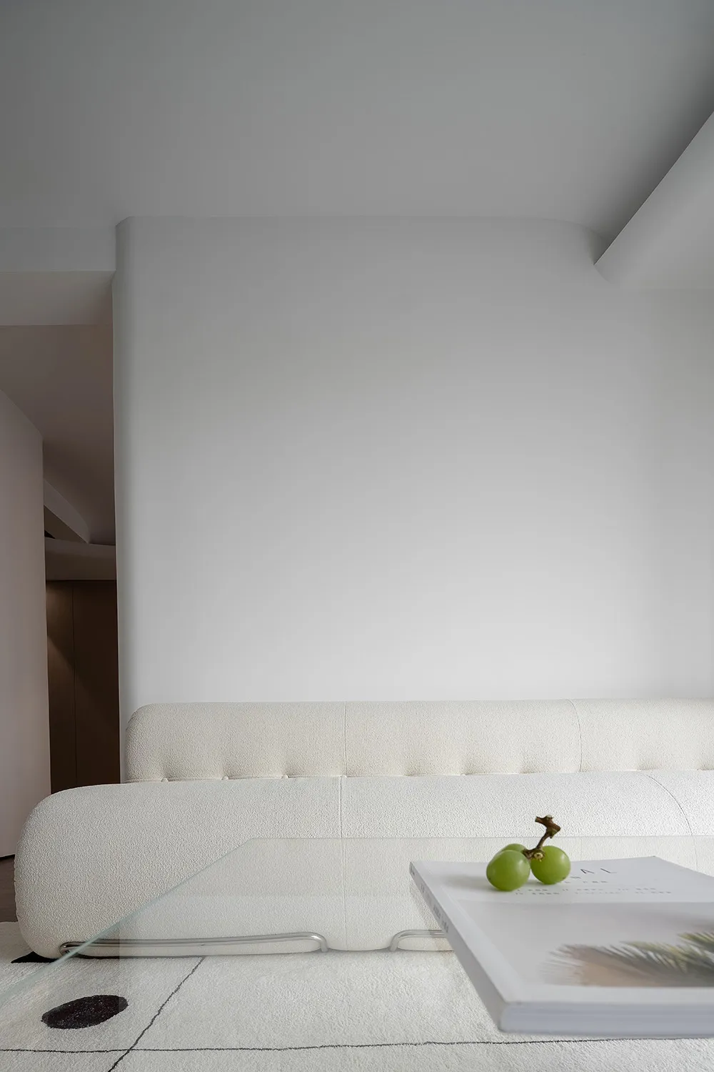 A modern white sofa lounge with a glass table displaying grapes and a book.