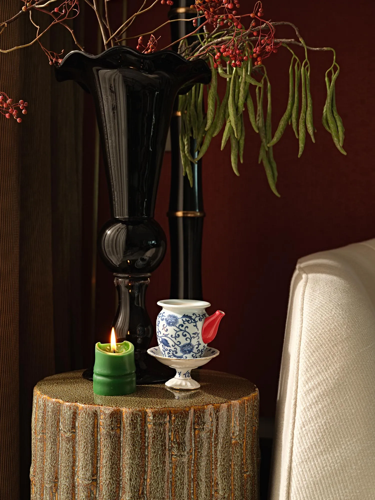 一個陶瓷茶壺,紅色壺嘴、藍色花卉圖案,以及白色壺身與茶托,置於帶有灰色紋理的木質桌面上