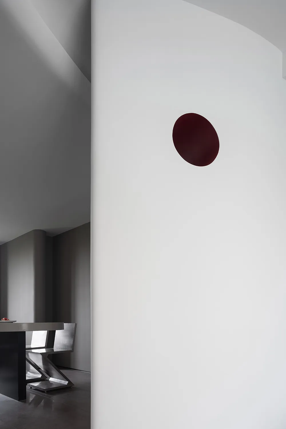Minimalist food court with red circular light fixture on a white wall and white flooring.