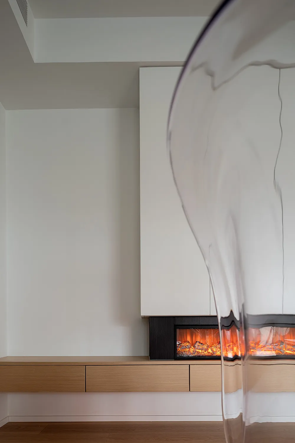 A minimalist living room featuring wooden furniture and a fireplace.