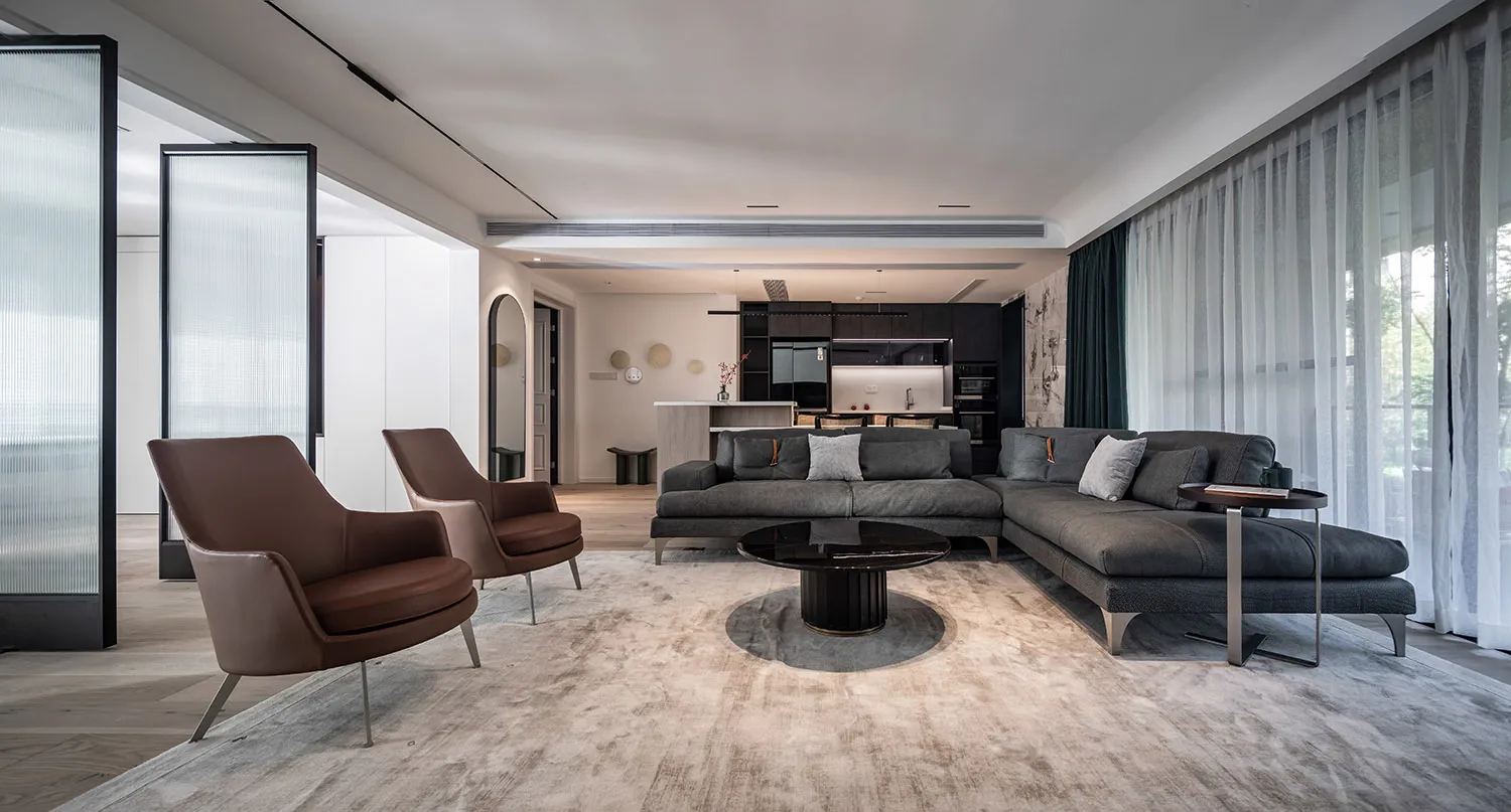 Contemporary living room featuring a sectional sofa, armchairs, and a round coffee table in a modern design style.