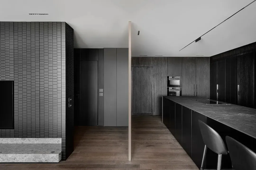 A modern apartment interior featuring a dark wood kitchen with marble countertops and backsplash.