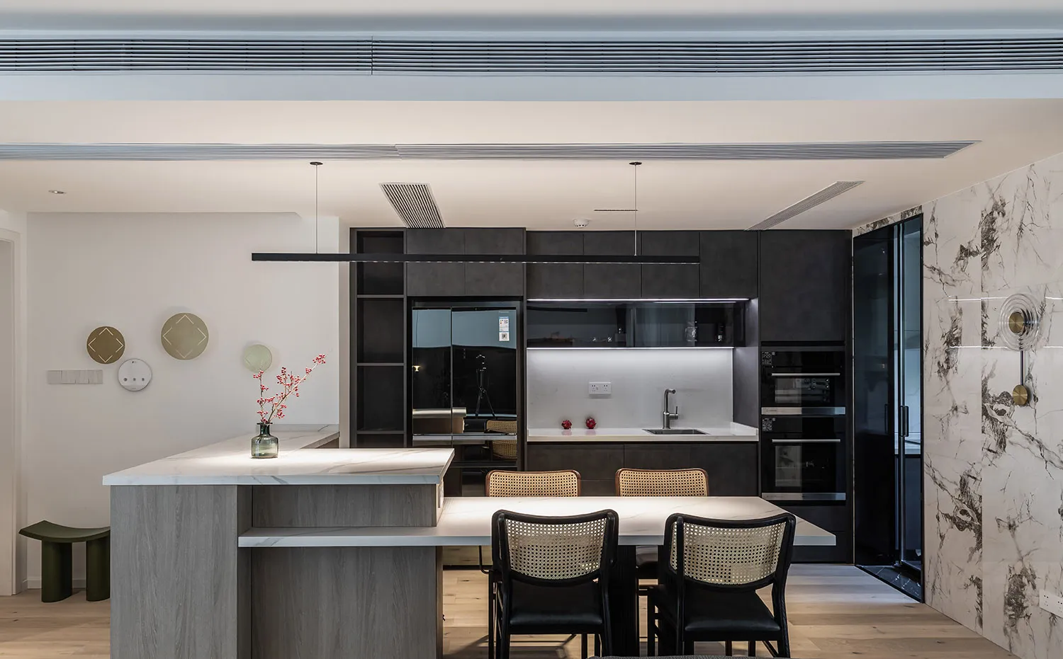 A modern residential kitchen with white marble countertops and black cabinets.