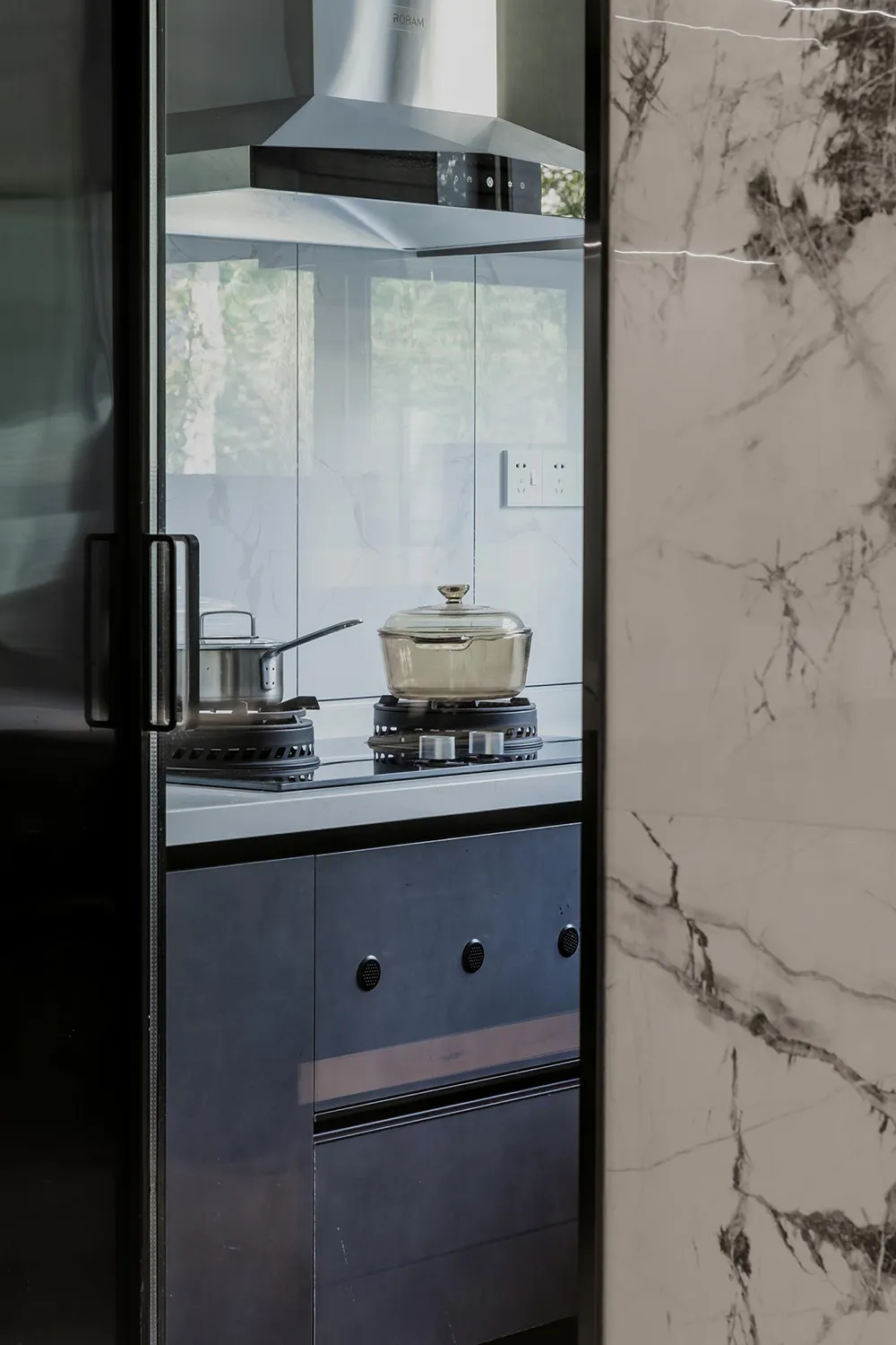 Modern kitchen featuring marble countertops and backsplash.