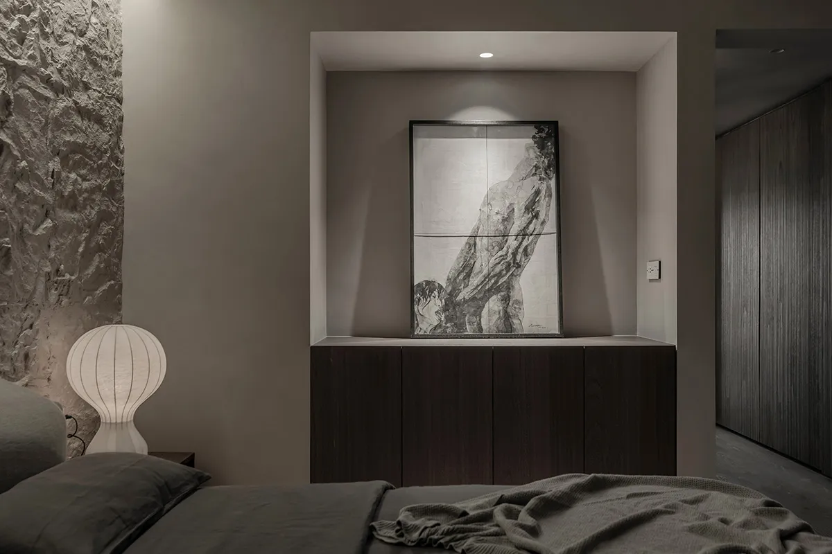 A modern, minimalist bedroom with dark wood furniture, gray bedding, and a textured wall.