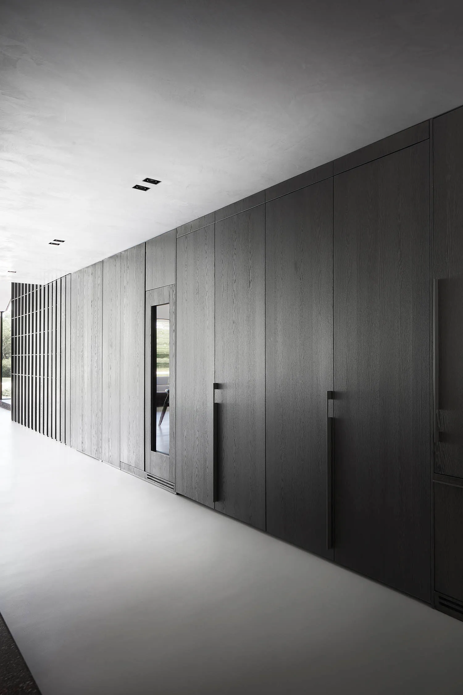 A modern minimalist bathroom with dark wooden cabinets and a white floor.
