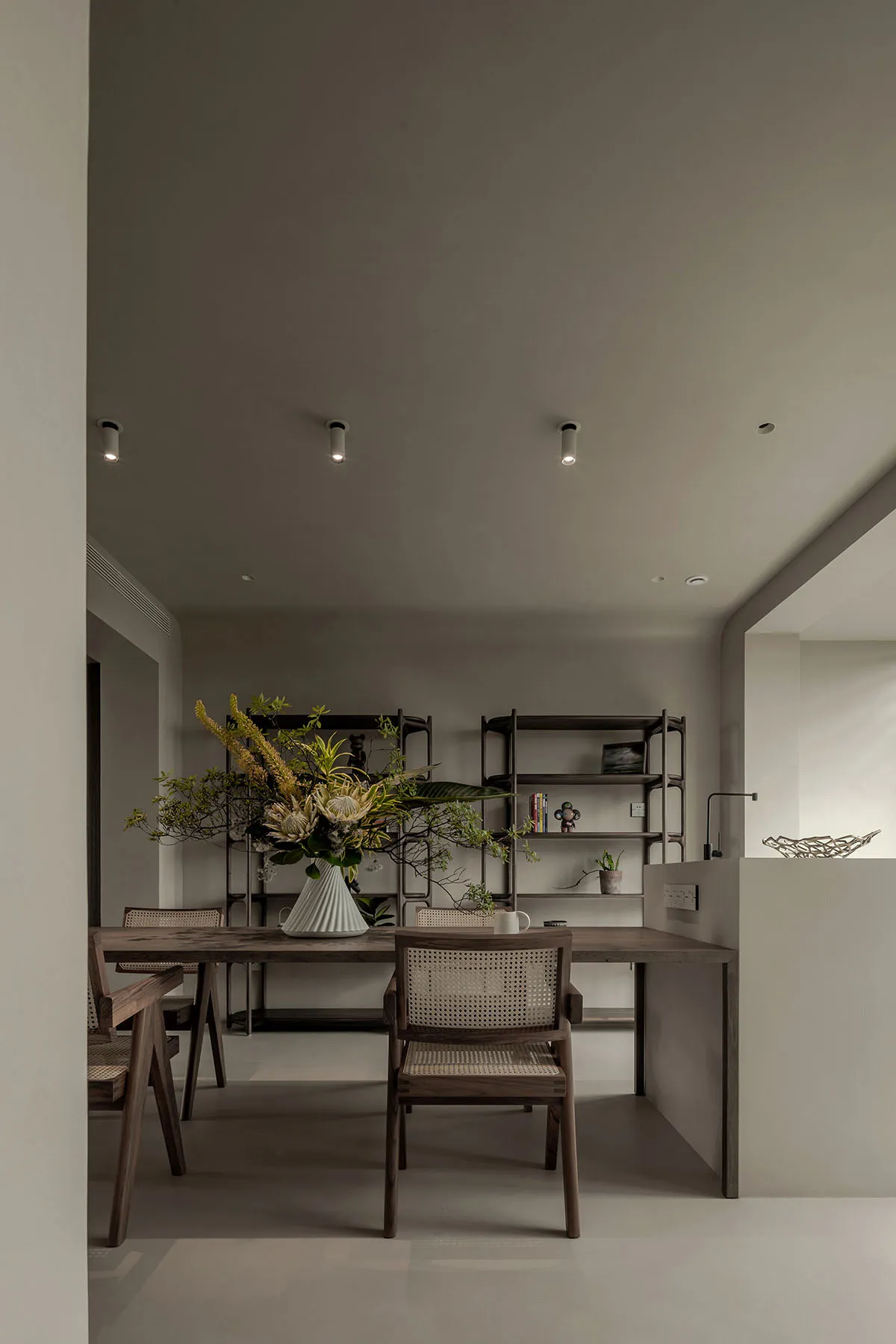 A modern, minimalist home office featuring wood furniture and a vase with floral arrangement.