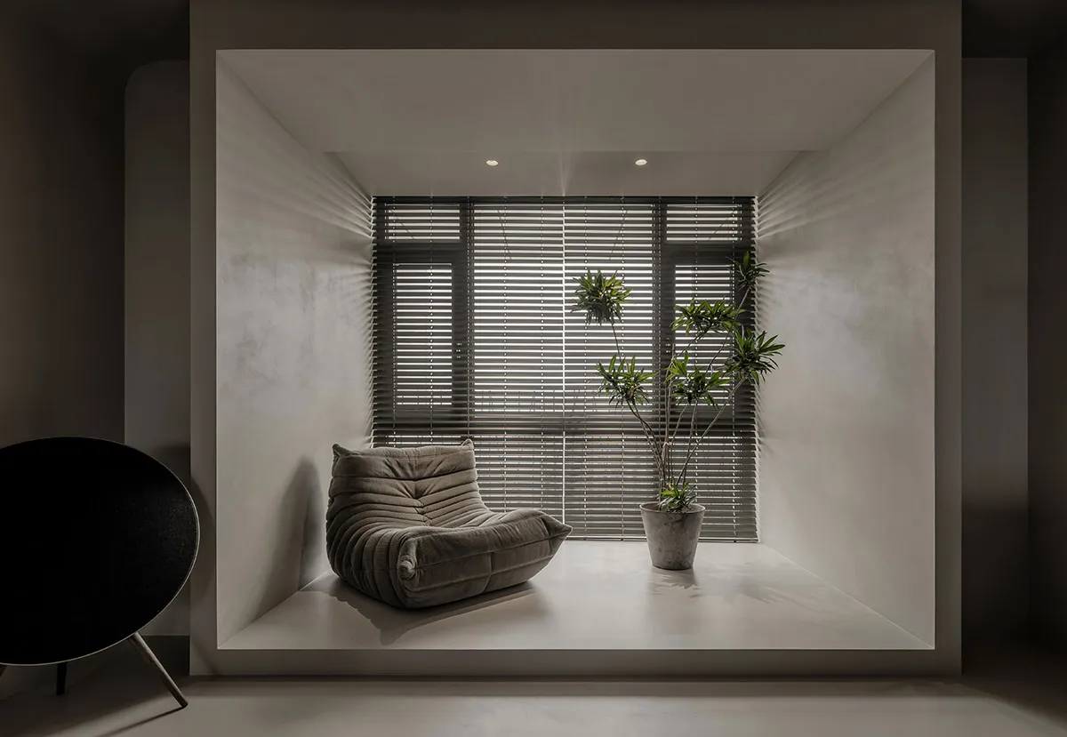 Modern minimalist window seat with a textured concrete finish and textured cushion, featuring a sleek black circular wood cha