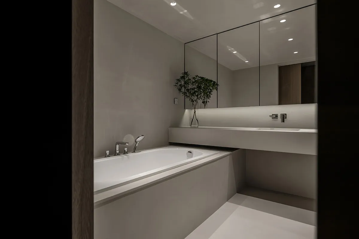 A minimalist modern bathroom with concrete walls and white fixtures.
