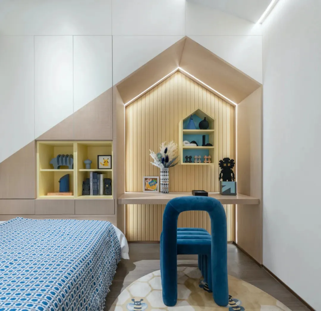 Modern, minimalist bedroom featuring blue accents, a blue upholstered chair, and a blue patterned bedspread.