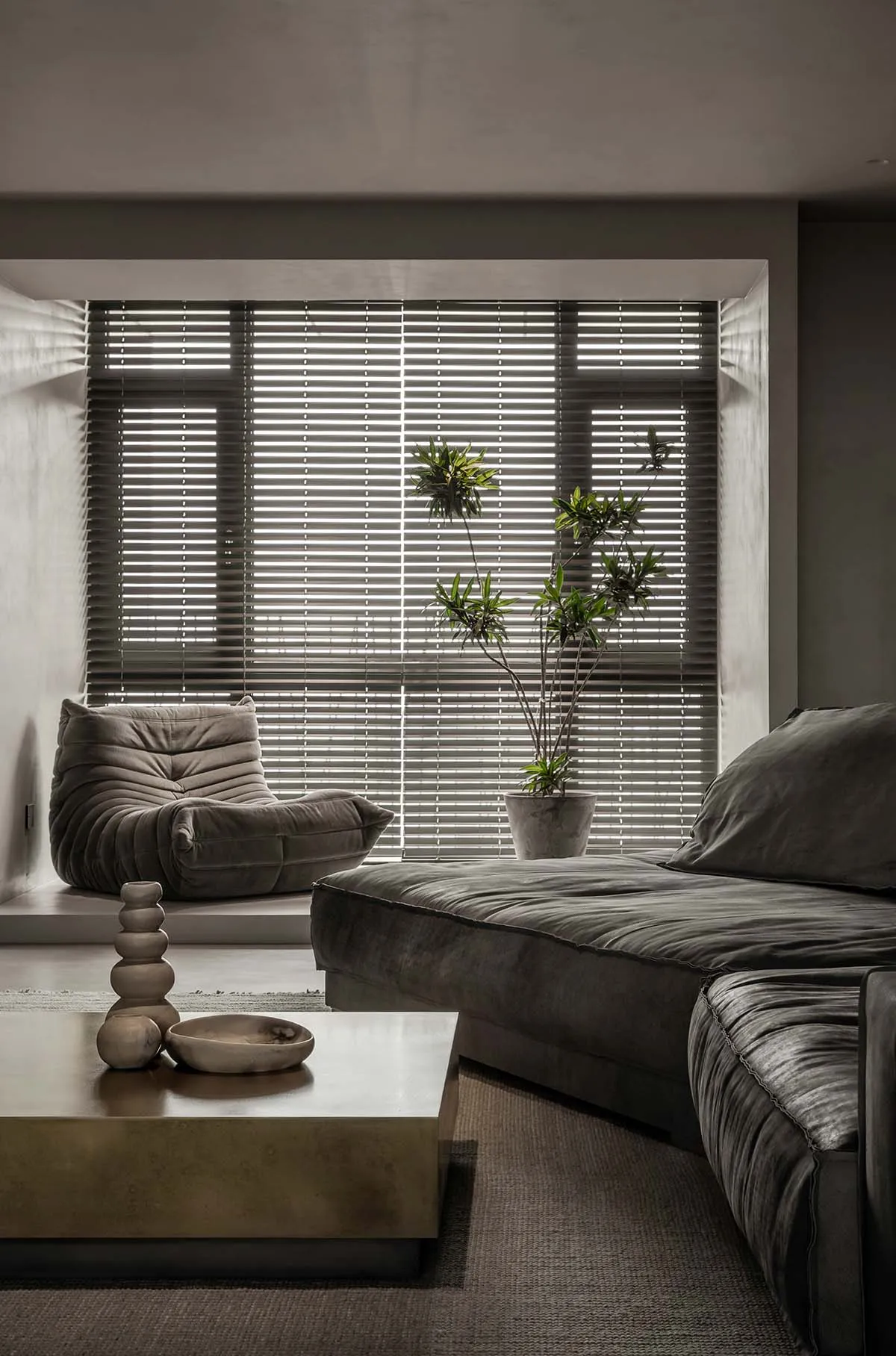 Modern minimalist living room featuring a plush velvet couch, a sleek concrete coffee table, and wooden accents on a polished