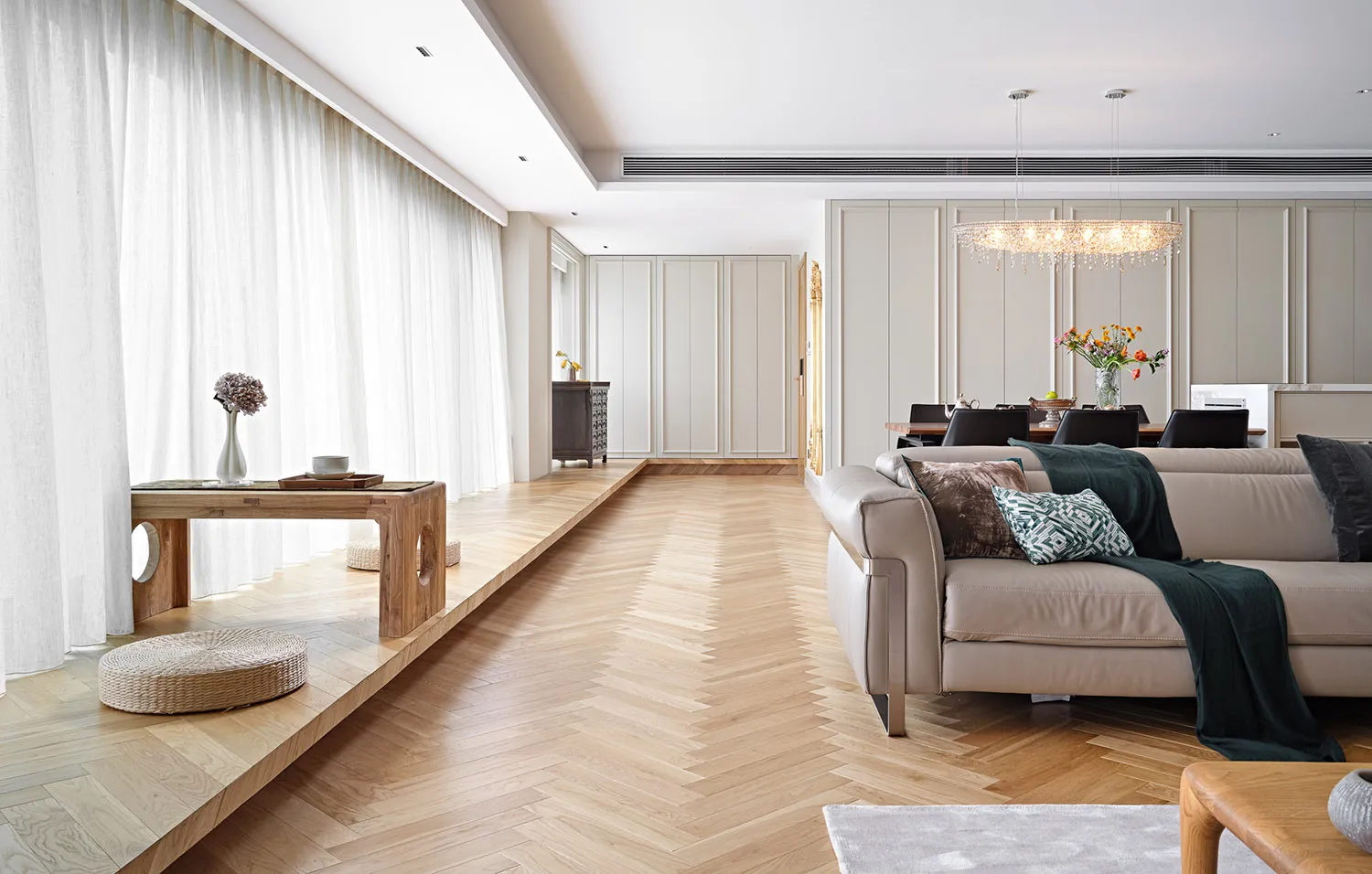A spacious, contemporary living room with a wooden floor, modern furniture, and neutral color palette.