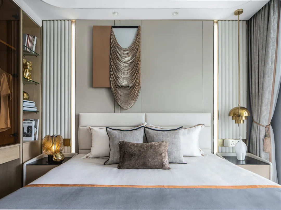 A modern minimalist bedroom featuring a bed with textured cloth, metallic pendant lights, and a gold-framed mirror.