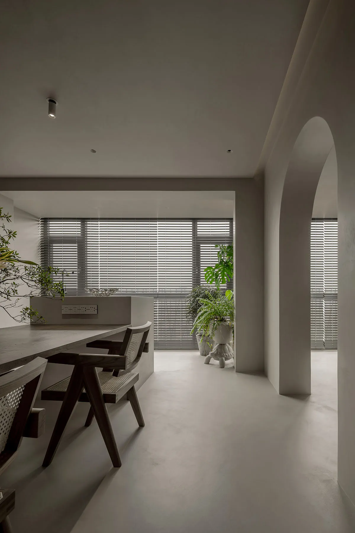 Minimalist residential dining area with concrete floor, wooden table, and chairs.