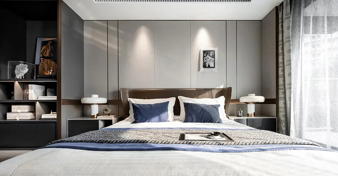 An elegant, minimalist bedroom with a white bed, grey paneling, and a mix of white and grey decorative elements.