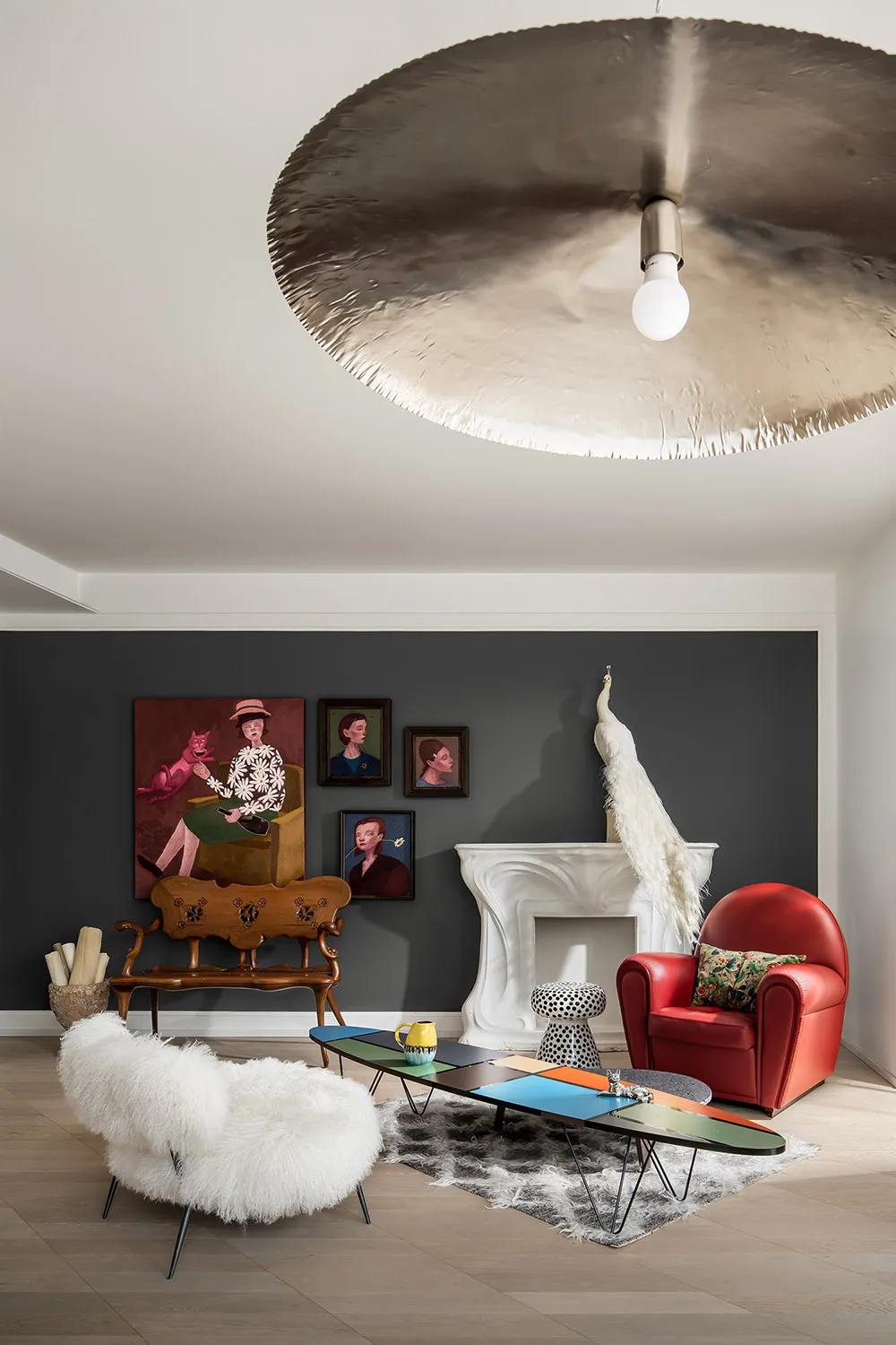 A modern living room with white walls adorned by red couch, white fur flooring, and white feathers on a coffee table.