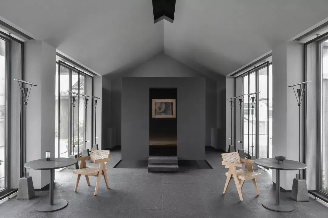 Modern industrial waiting area with concrete walls, wooden furniture, and vertical windows