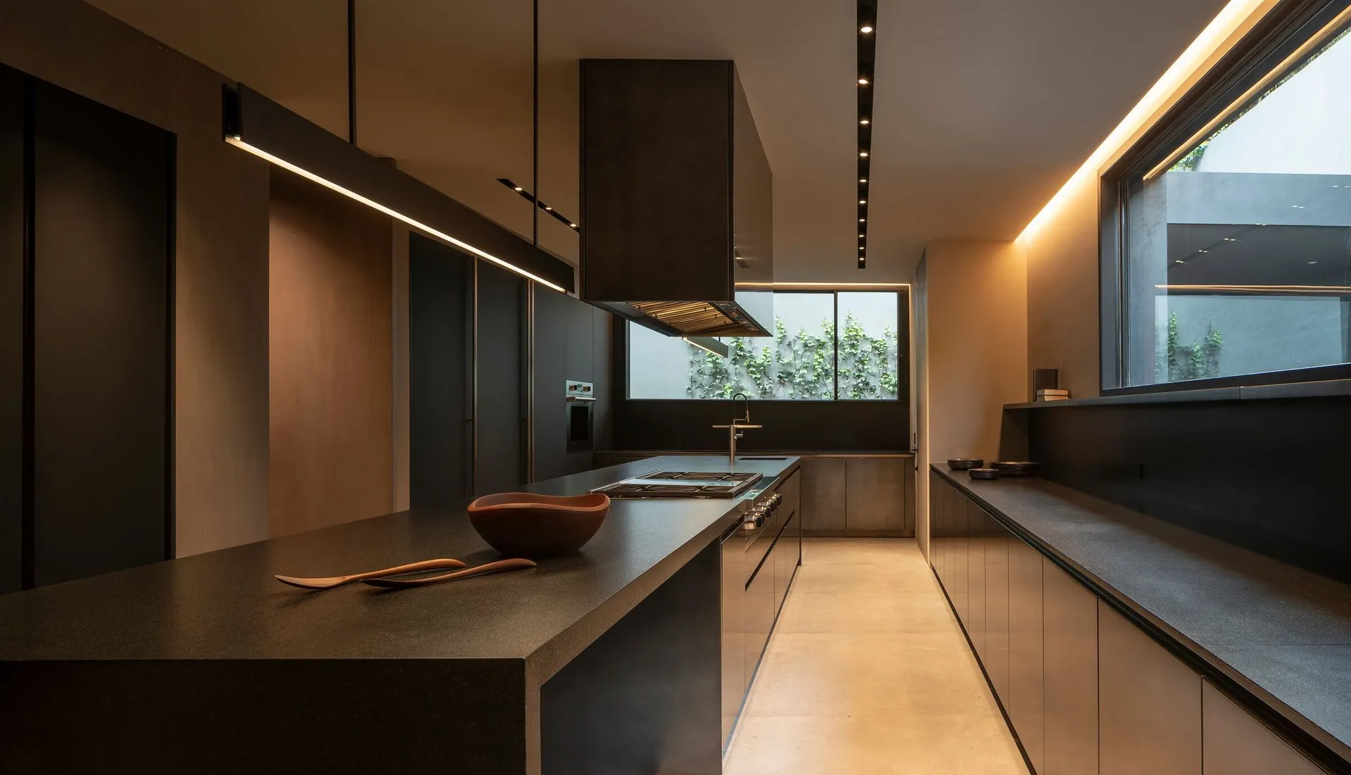 A modern, minimalist kitchen with concrete countertops and a large window.