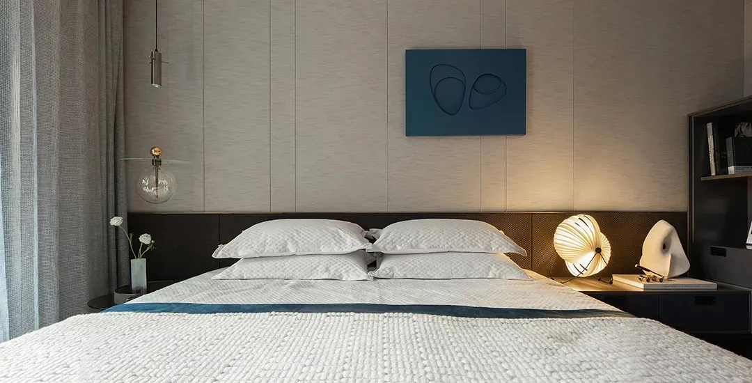 A modern bedroom featuring a textured fabric bed with white curtains and a minimalist design.