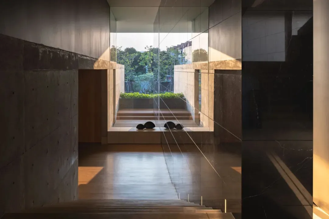 A serene modern living space with concrete walls and a view of greenery outside.