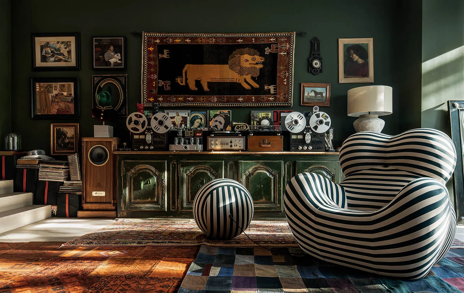 A cozy living room with a striped armchair, a brass tea lamp, and various musical equipment.