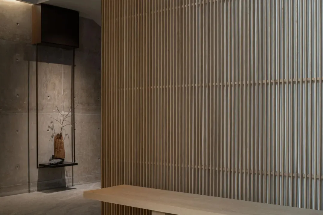 A minimalist interior design featuring wooden accents, including a wooden bench against a wooden-paneled wall.