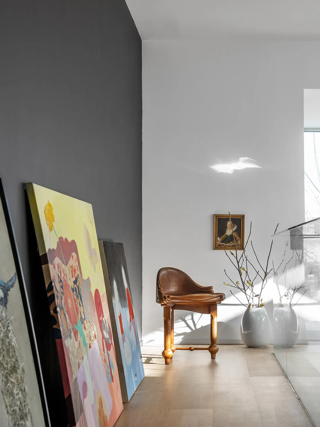 A modern interior design space featuring a wooden chair and colorful artwork.
