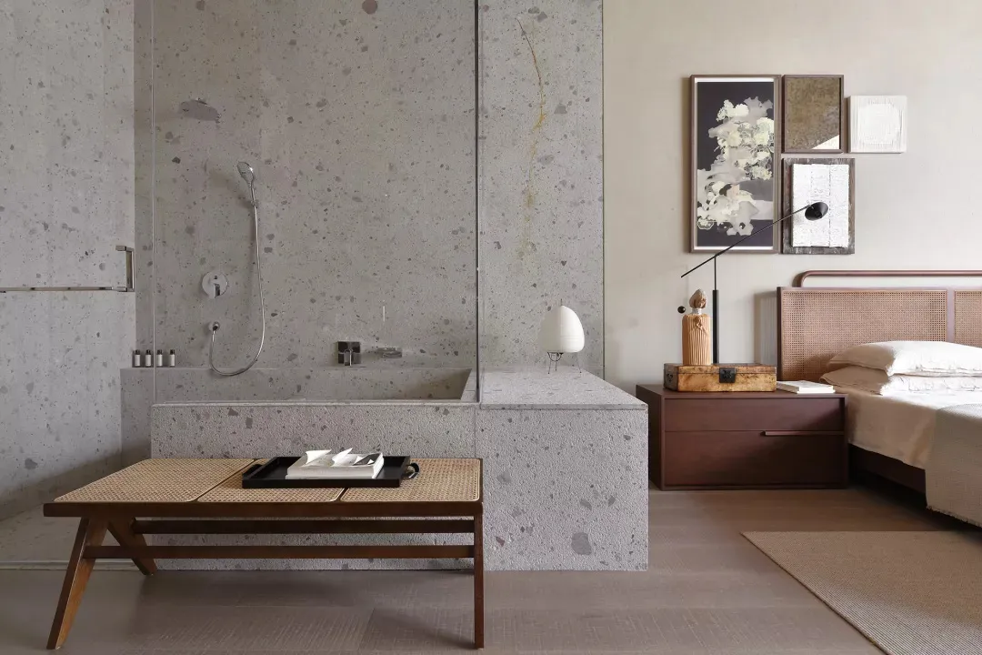 Modern bathroom with a concrete wall, a glass-enclosed shower, a floating nightstand, and a woven headboard bed.