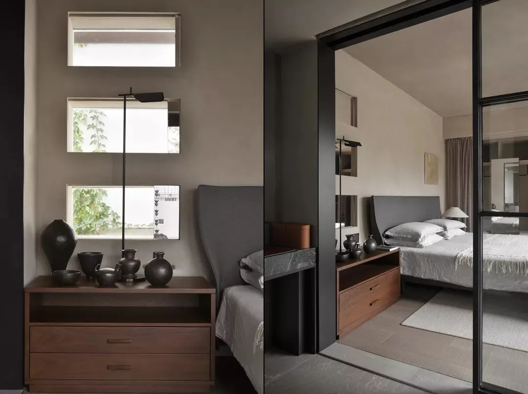 A modern, minimalist bedroom with dark wood furnishings, metal accents, and a large window.