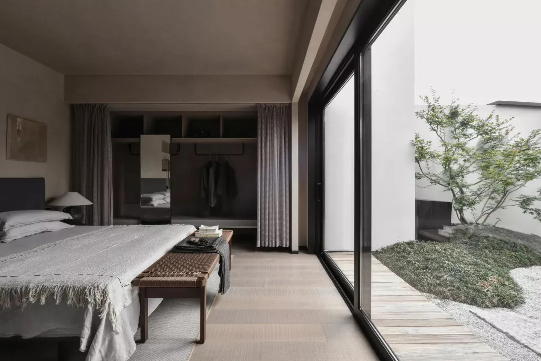 A modern minimalist bedroom featuring wooden flooring and furniture.