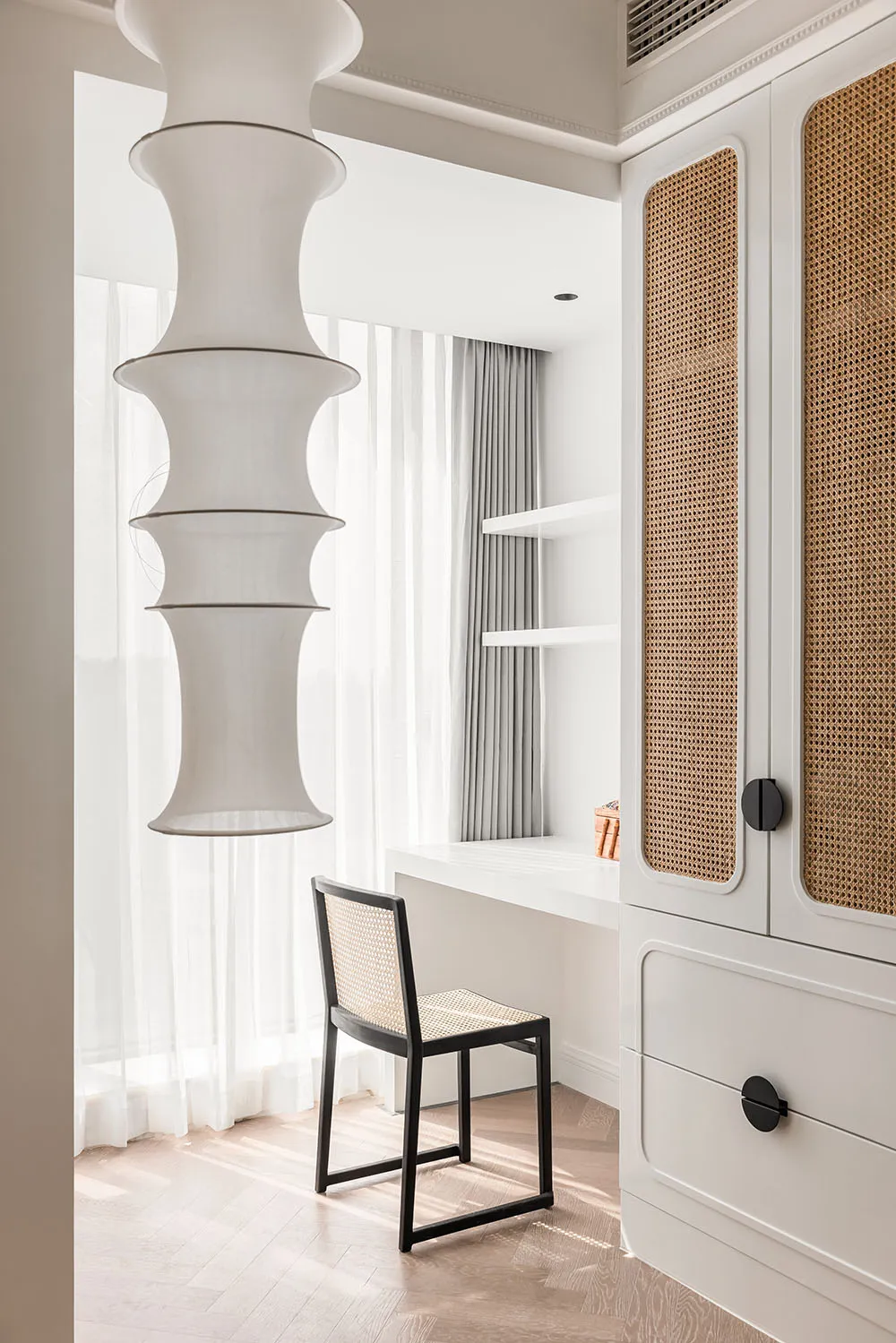 A minimalist home office with light wood cane blinds, white curtains, and white walls, featuring solid white furniture and a 