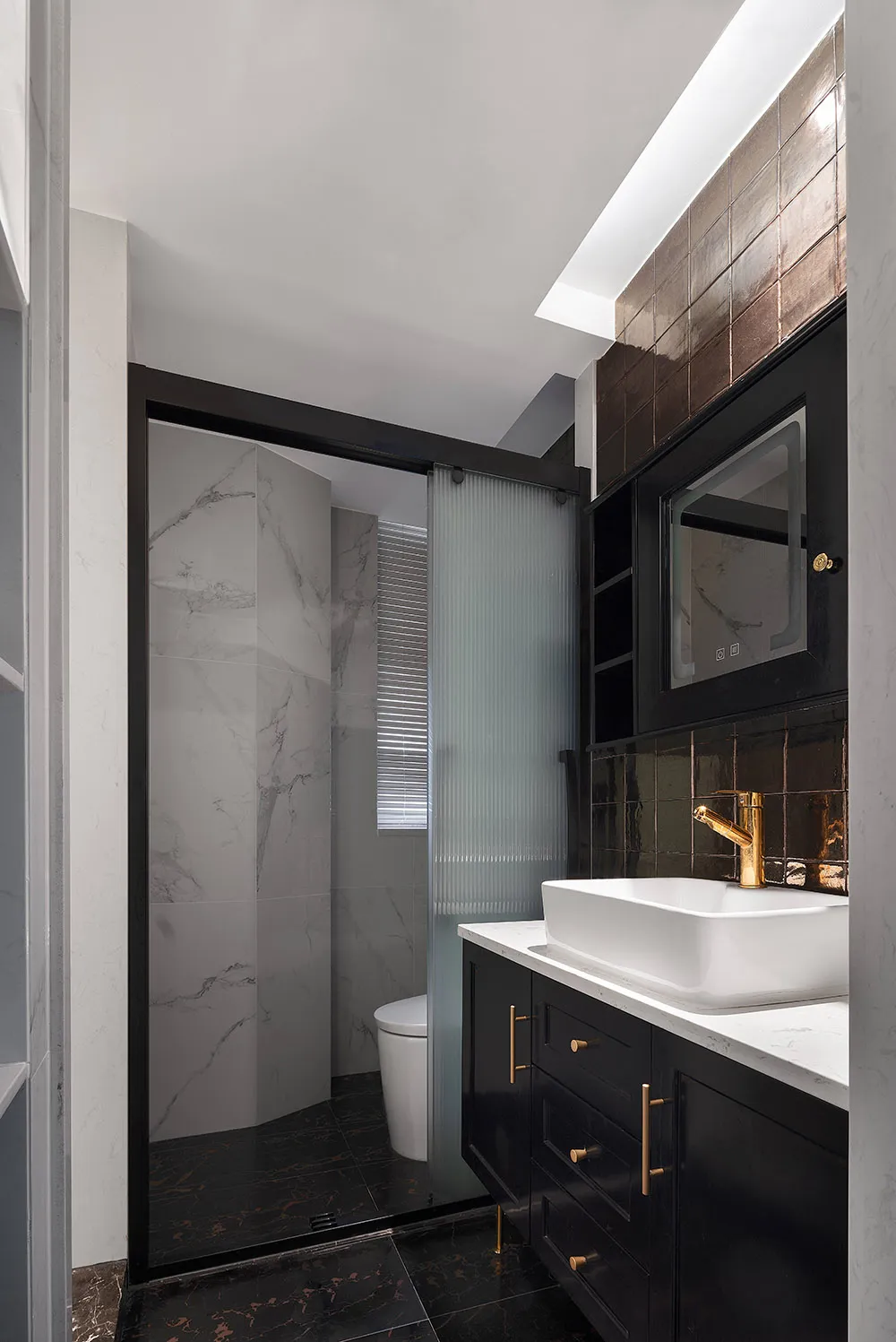 Modern bathroom interior with marble and black tile walls and floor, featuring a sink with a white countertop and black cabin