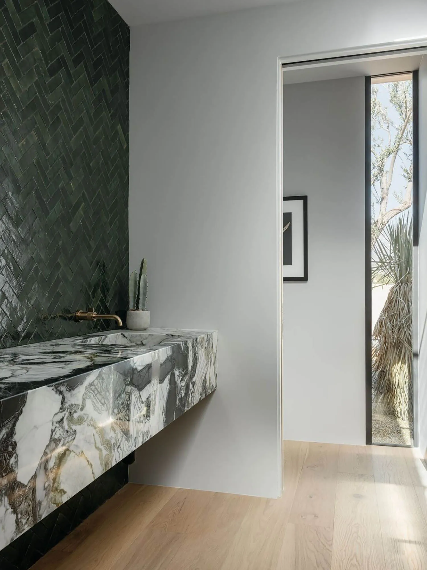 A modern bathroom with a marble countertop and black tiled walls.