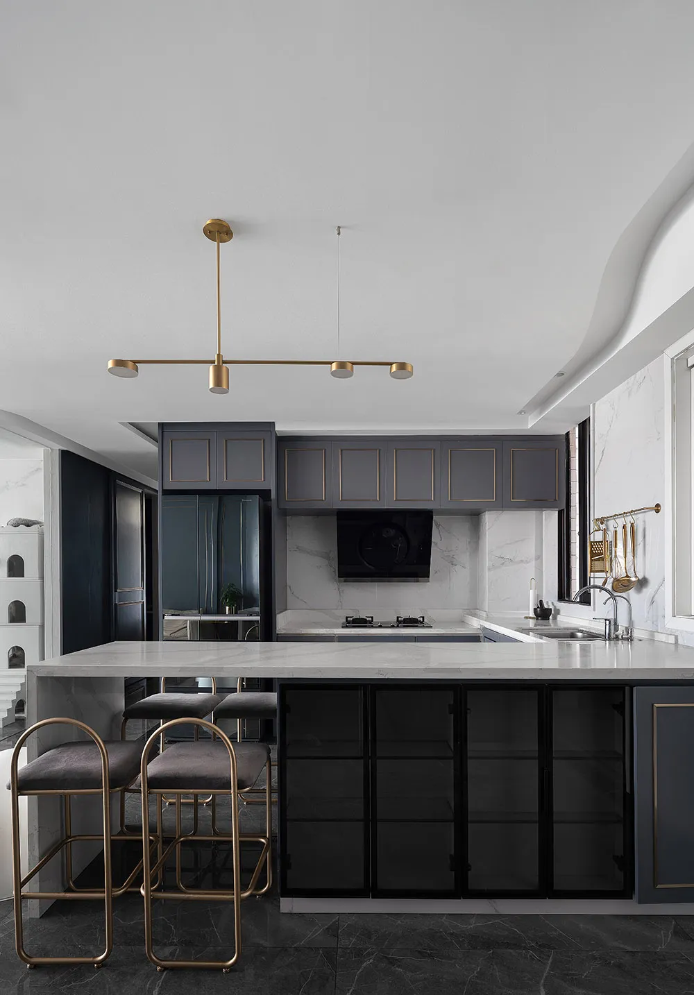 A modern kitchen featuring marble countertops and decorative lighting fixtures.