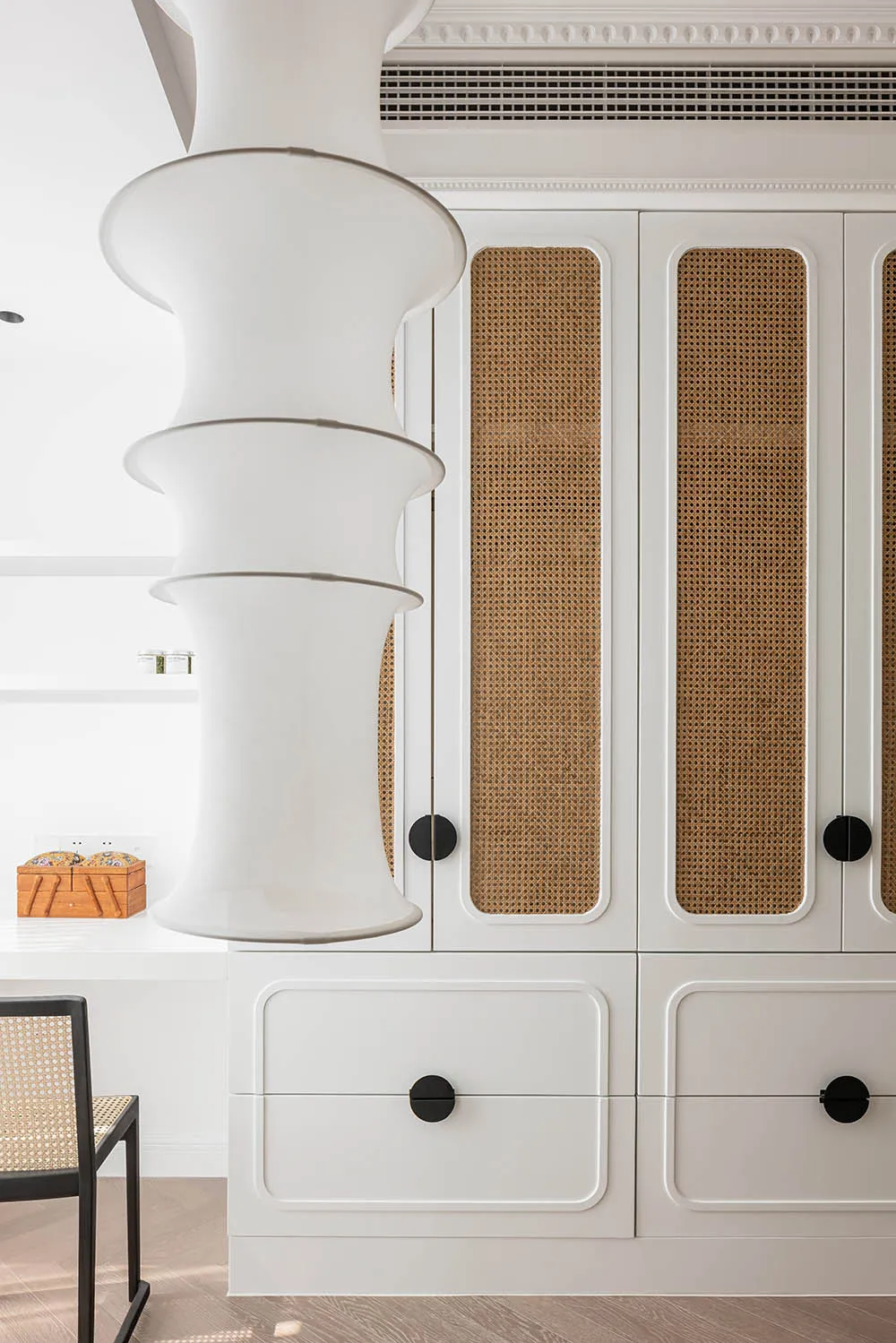 Modern white closet with rattan trim and black knobs.