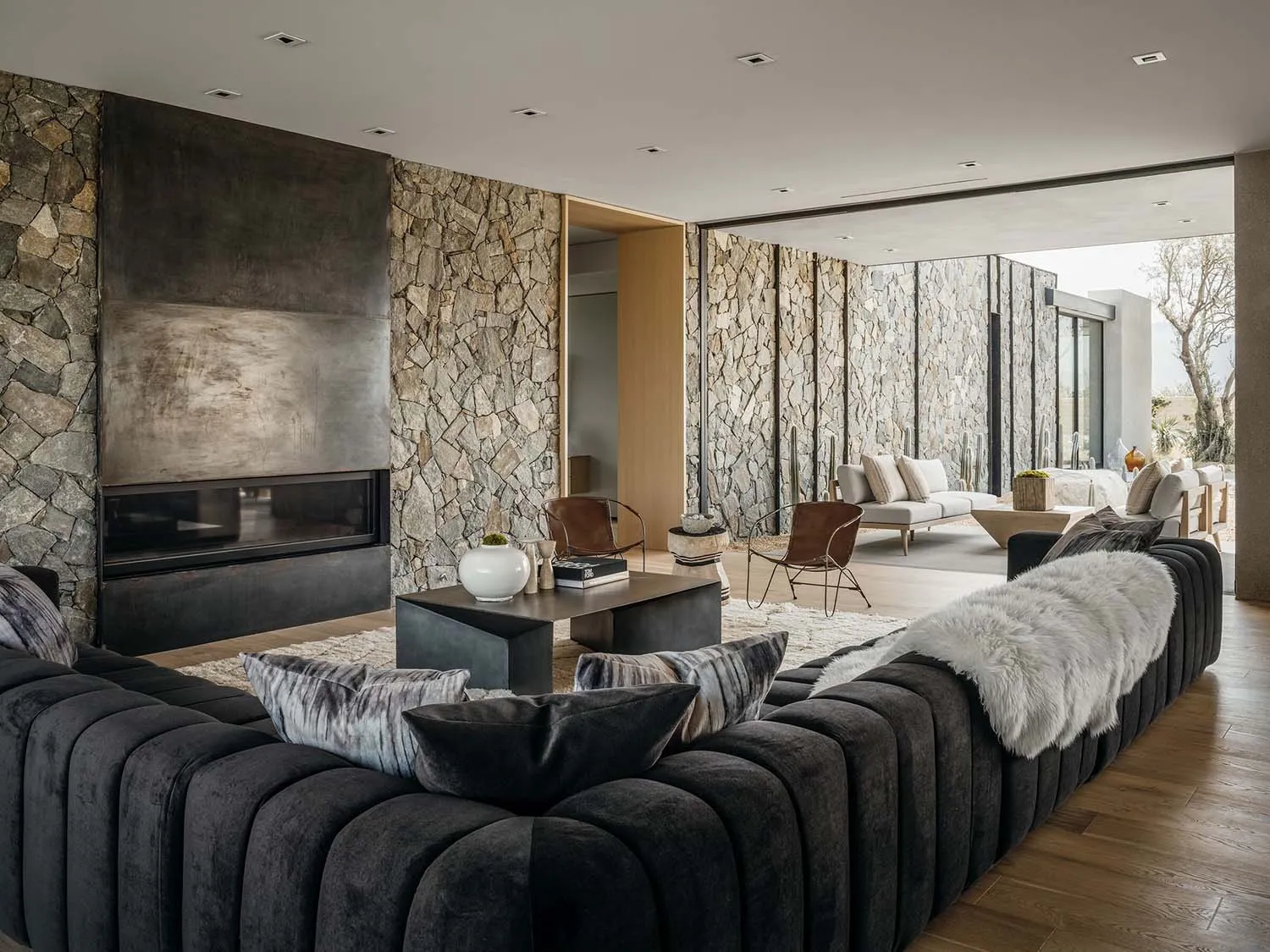 A modern living room with stone walls, a fireplace, and plush seating.