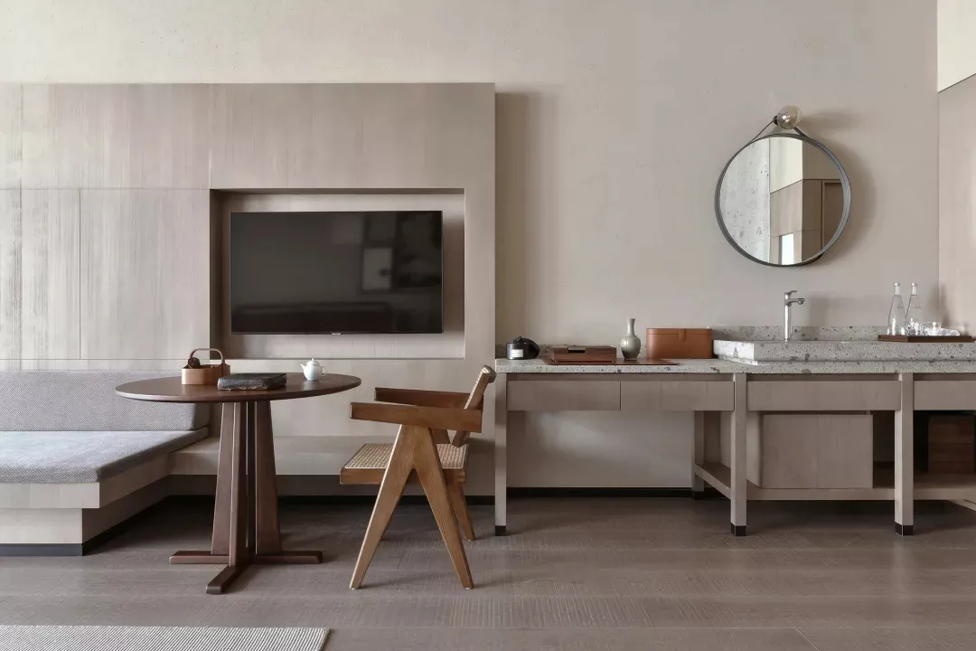 Modern residential interior with a combination of wooden furniture and cement flooring, featuring a seating area, round table