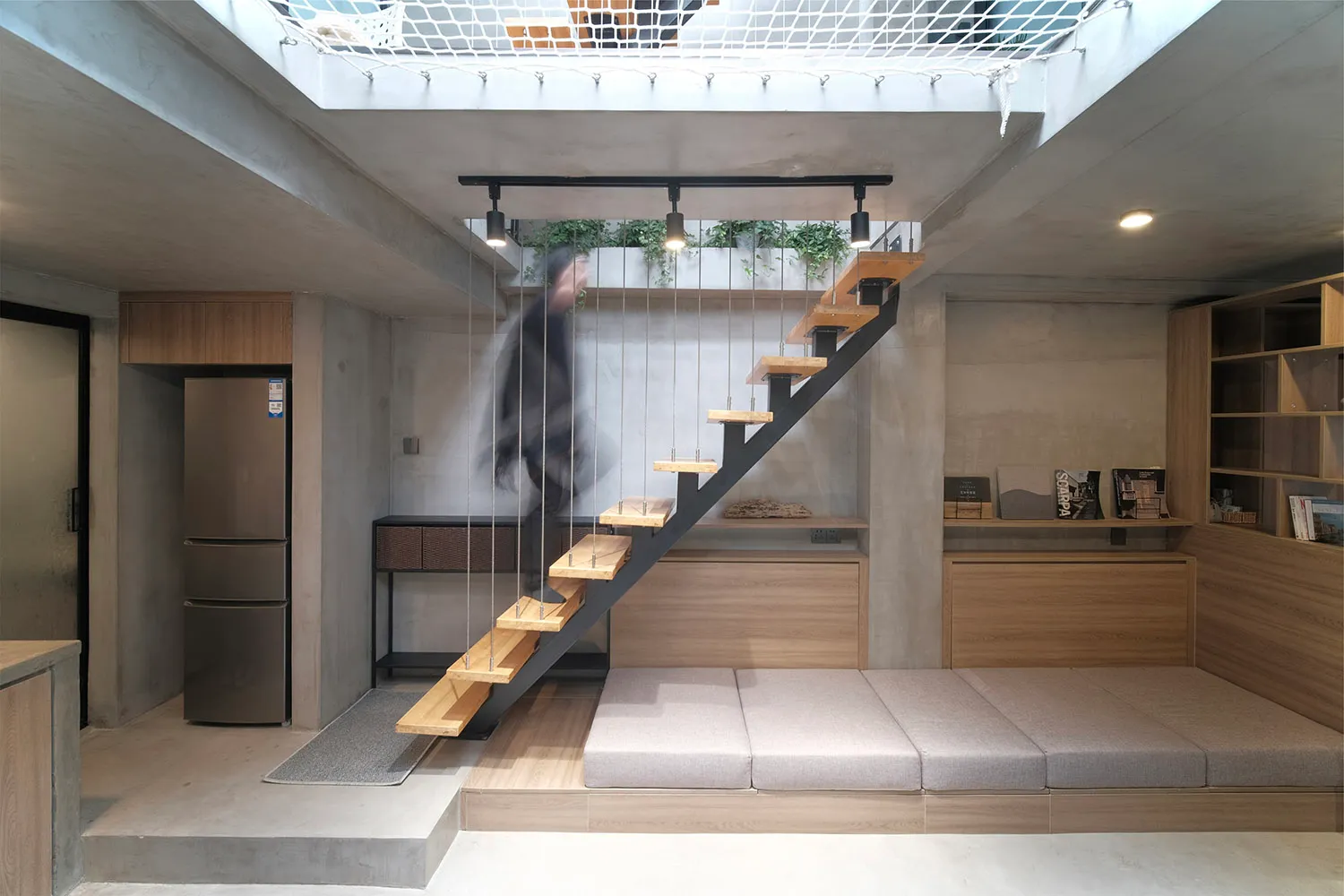 A modern living room featuring industrial design elements like concrete walls, wooden furniture, and metal stairs.