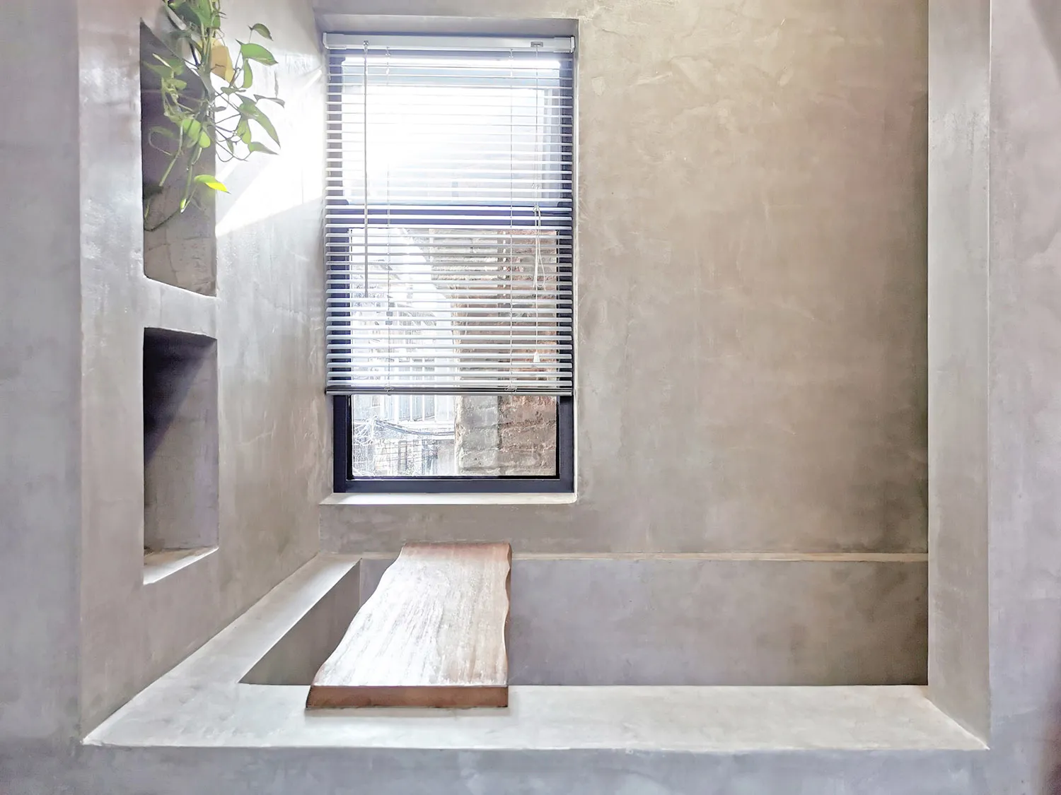 Window with blinds in a modern minimalist bathroom made of concrete.