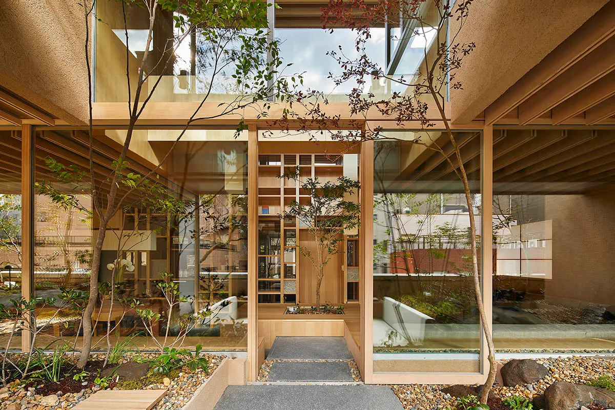 A minimalist residential courtyard featuring glass walls, wooden flooring, and concrete elements.