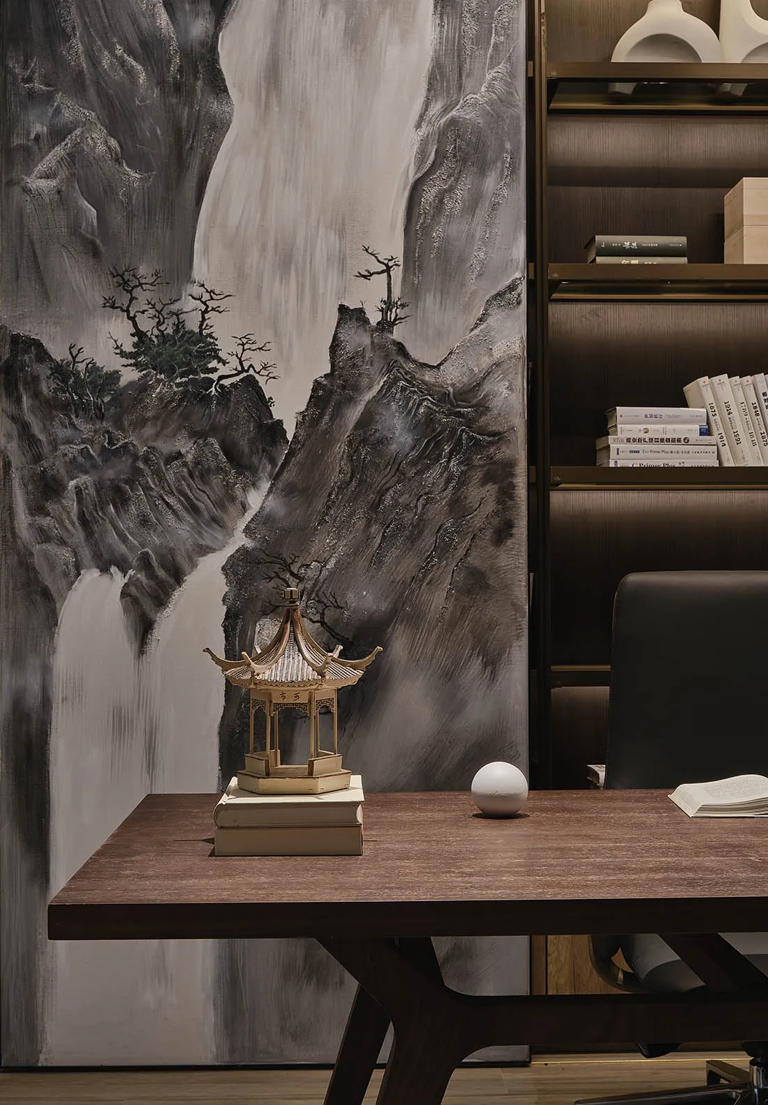 A modern office desk with a wooden top and a minimalist design sits in front of a mural depicting a mountain landscape. The d