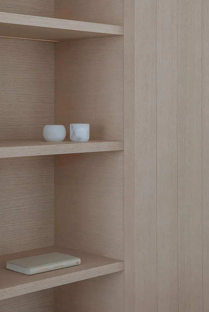 Modern minimalist shelving unit constructed from natural wood, featuring open shelves.