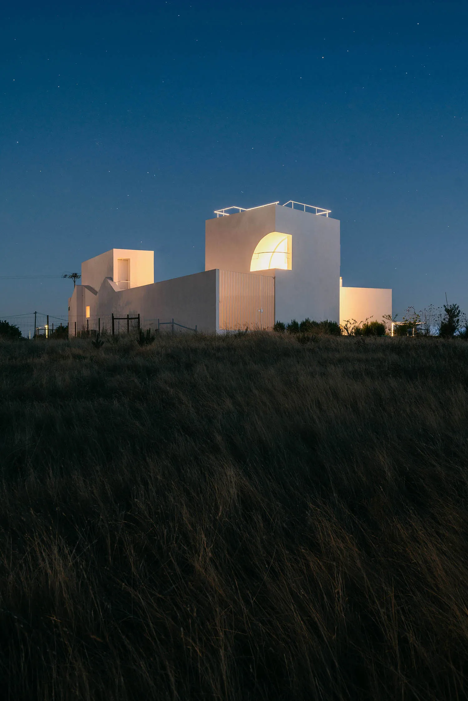A minimalist building with a concrete exterior at night.