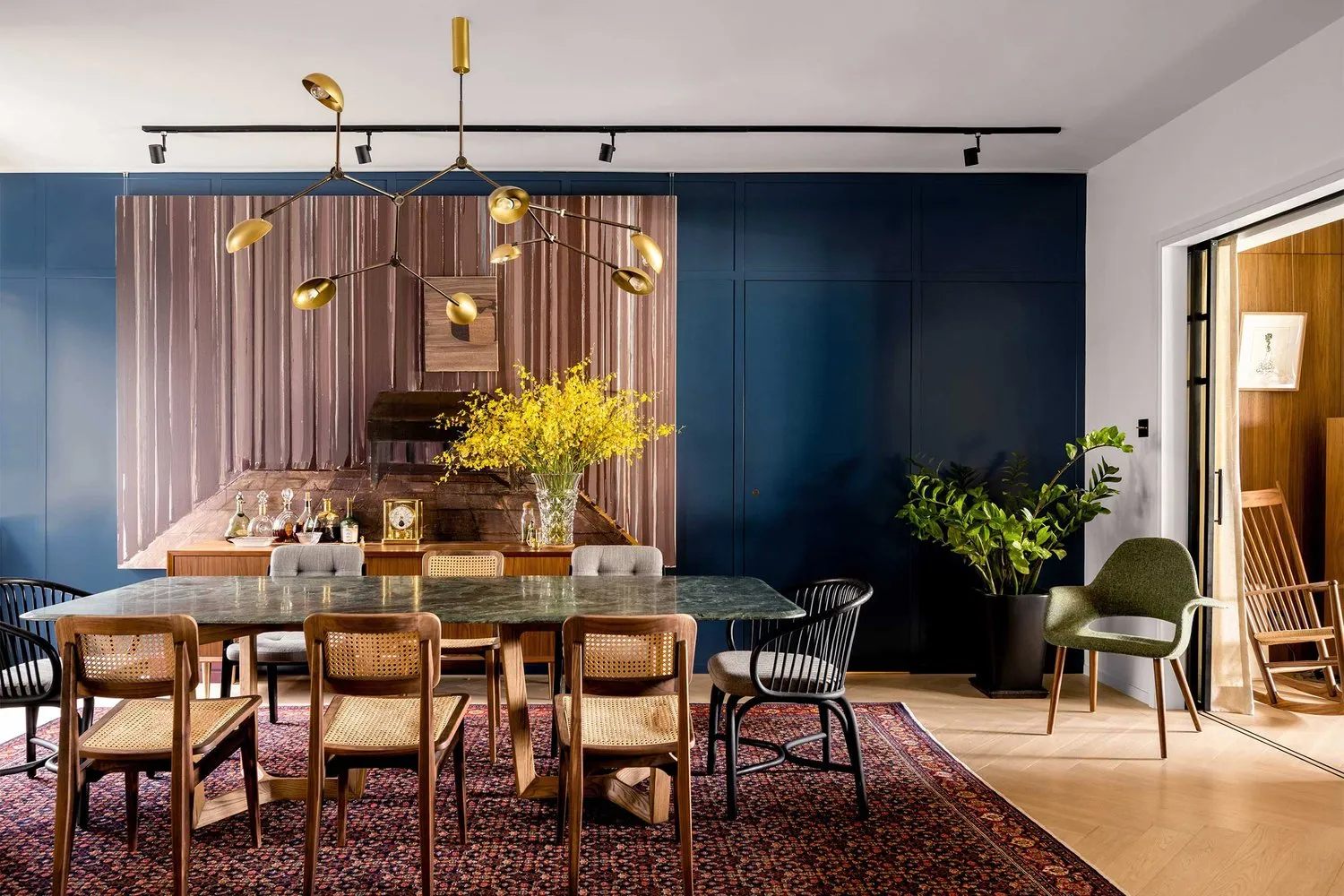 Modern dining room with marble table, wooden chairs, and metal lighting fixture.