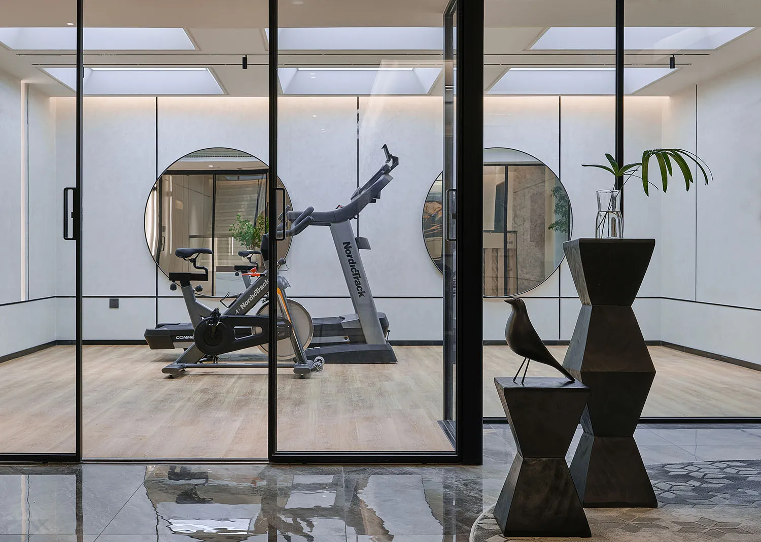 Modern industrial home gym with wooden floors and minimalist decor.