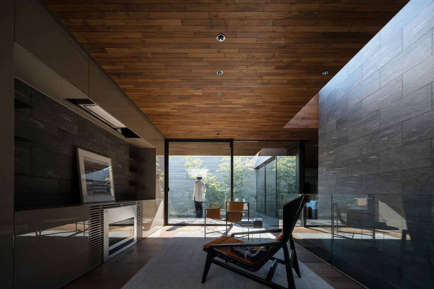 Modern living room with glass walls and wooden floor and ceiling.