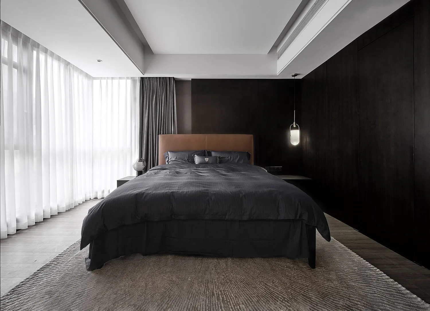 Modern minimalist bedroom featuring black and white color scheme with textured cloth bedding and a large window.
